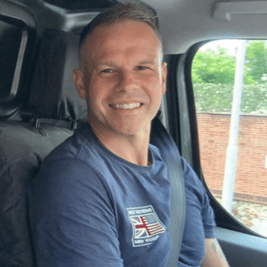 Martin Wicks sitting in van seat. Smiling and introducing his plumbing services