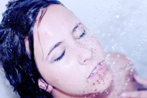 lady showering with water cascading down onto her face