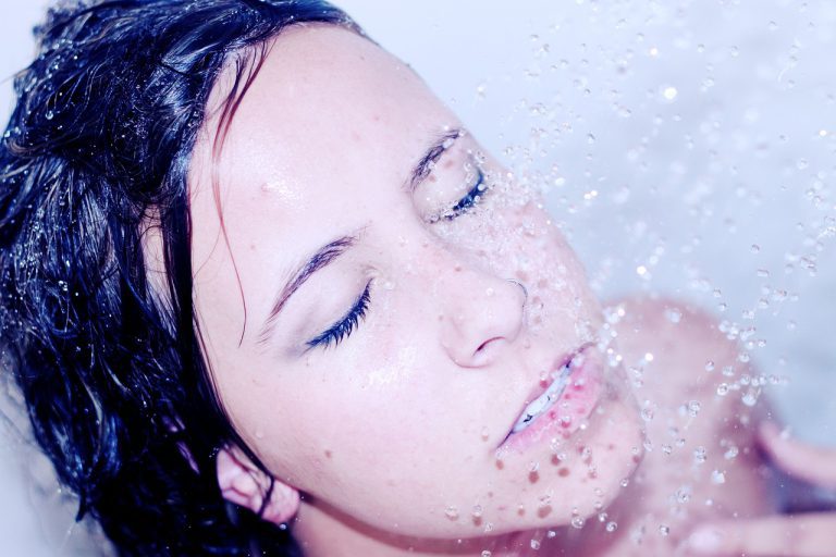 lady showering with water cascading down onto her face