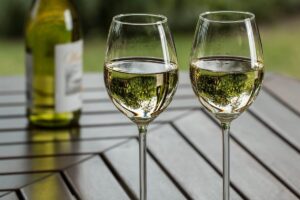 Two clean wine glasses half full sitting on wooden table outdoors